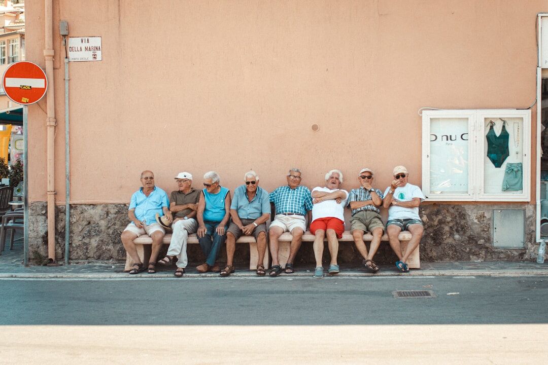 Group of smiling senior citizens sitting together outdoors on a sunny day